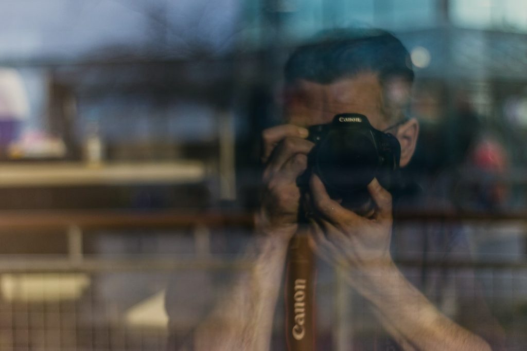 person taking a picture with a Canon camera, with the reflection in the mirror showing